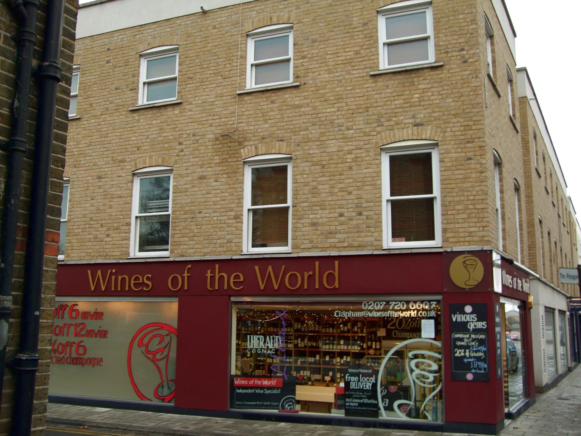 Corner wine shop with maroon fascia beneath a yellow brick block on a Clapham street, near The Polygon