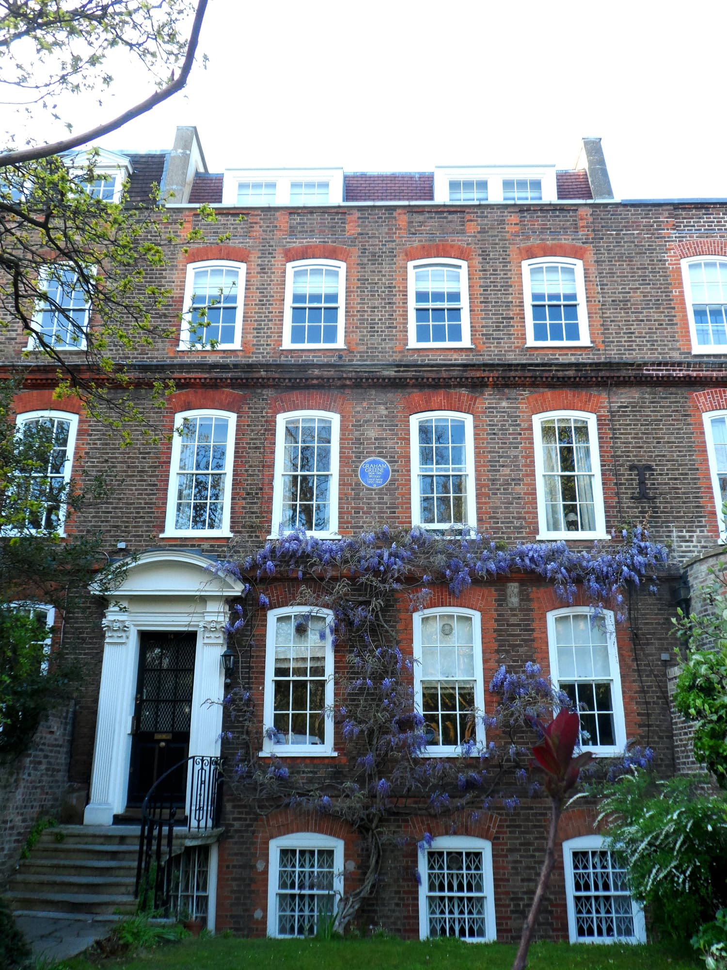 Georgian brick townhouse with wisteria across the facade, a blue plaque for Graham Greene and number 14 on the door