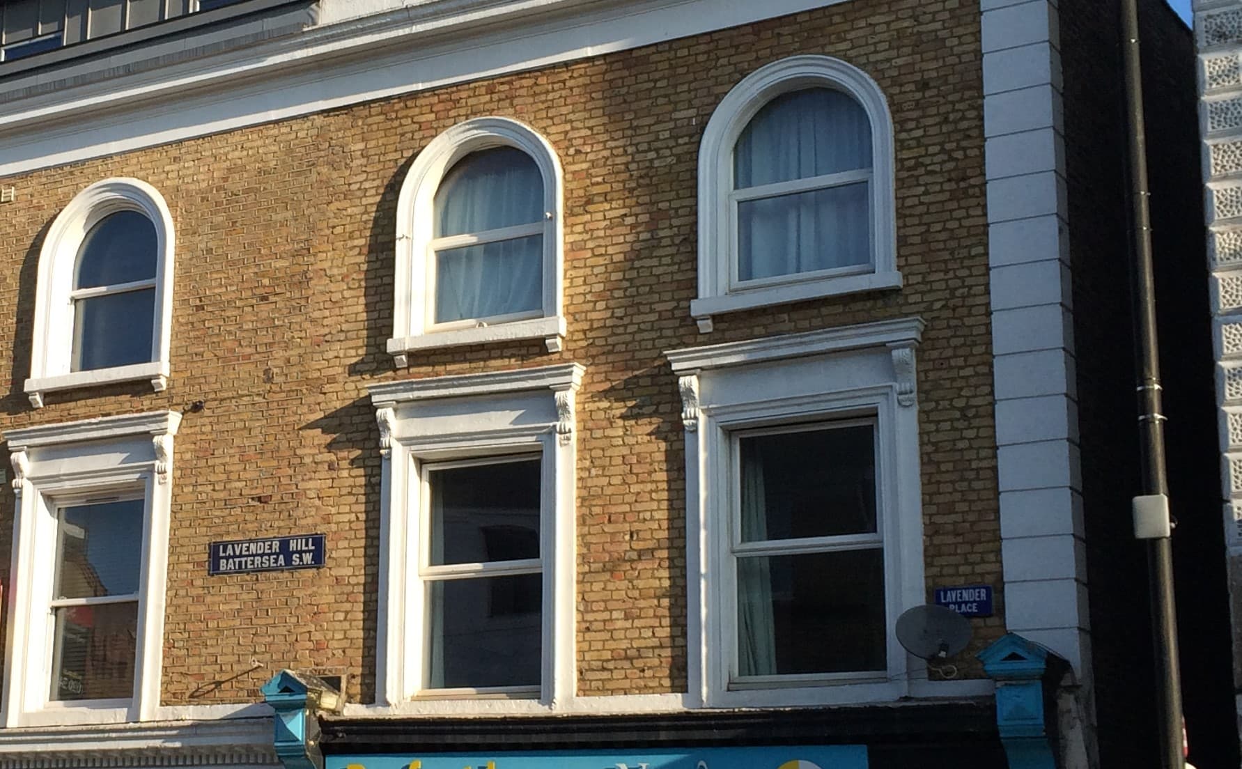 Yellow brick Victorian building with arched white windows and old Lavender Hill, Battersea S.W. street sign
